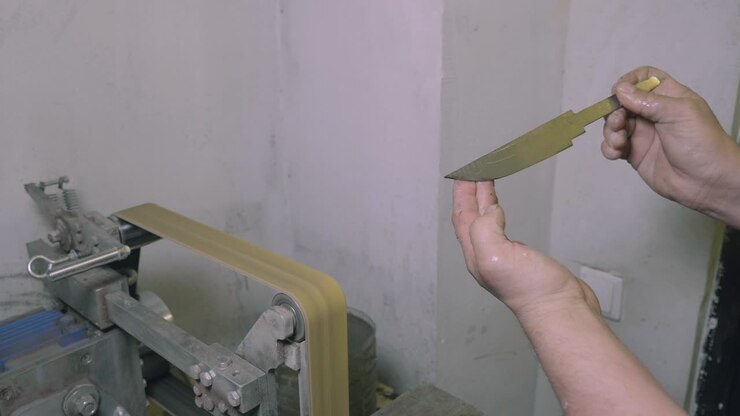 Employee holding in hand handmade knife in manufacturing hall close up