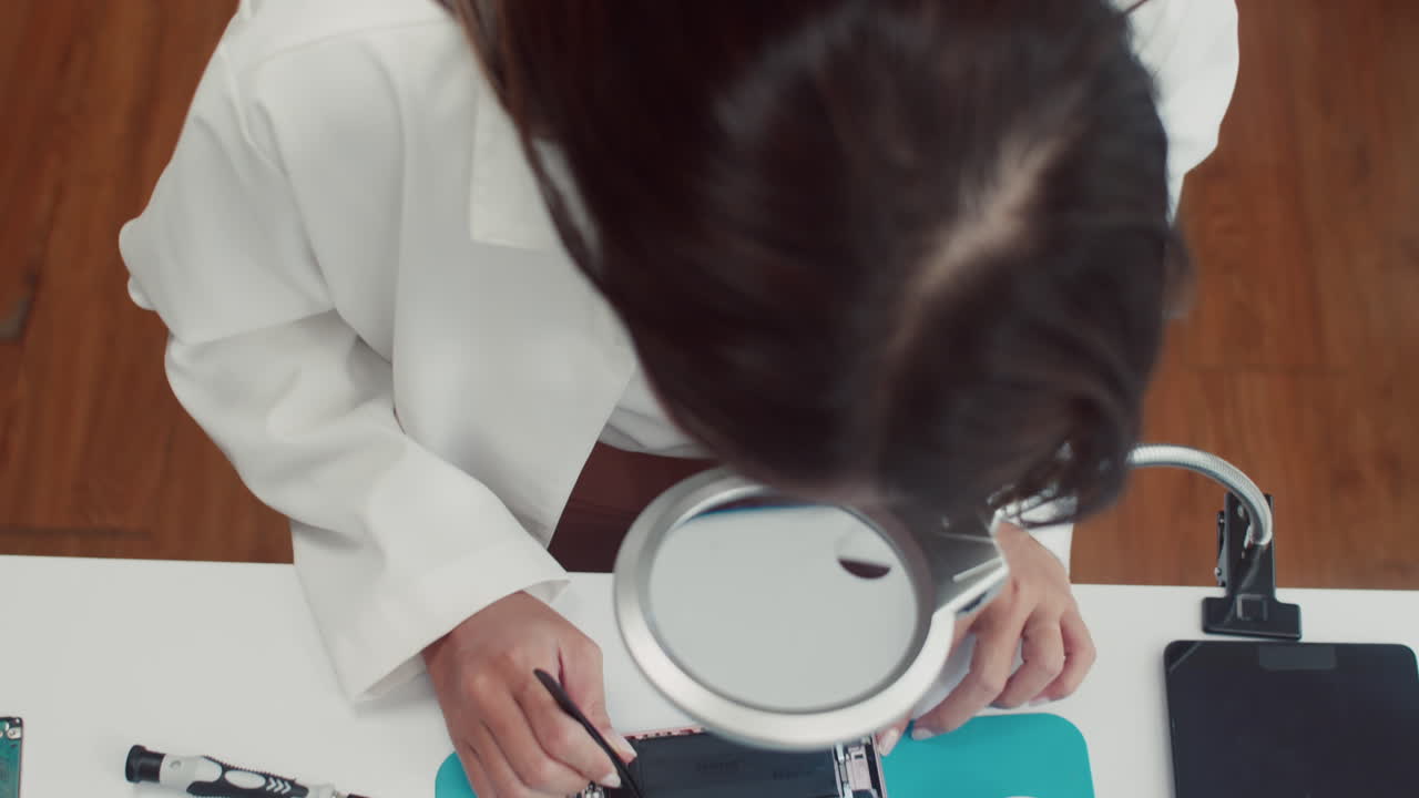 Woman Repairing Disassembled Phone Using Magnifying Glass
