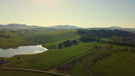 vuelo aéreo sobre campos soleados y montañas durante la puesta de sol