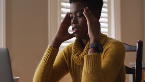 mujer afroamericana estresada usando una computadora portátil mientras trabaja desde casa