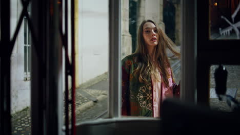 woman standing empty street late evening looking camera view from window glass.