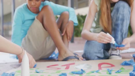 video of diverse schoolchildren making protest placards in schoolyard, copy space