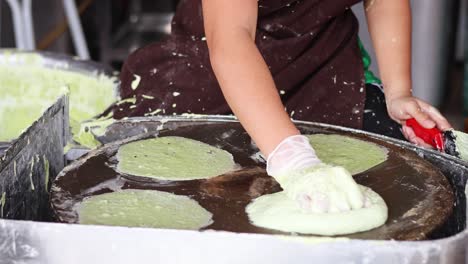 person preparing and cooking green crepes on griddle