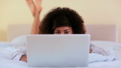 Gorgeous-brunette-lying-on-bed-using-laptop