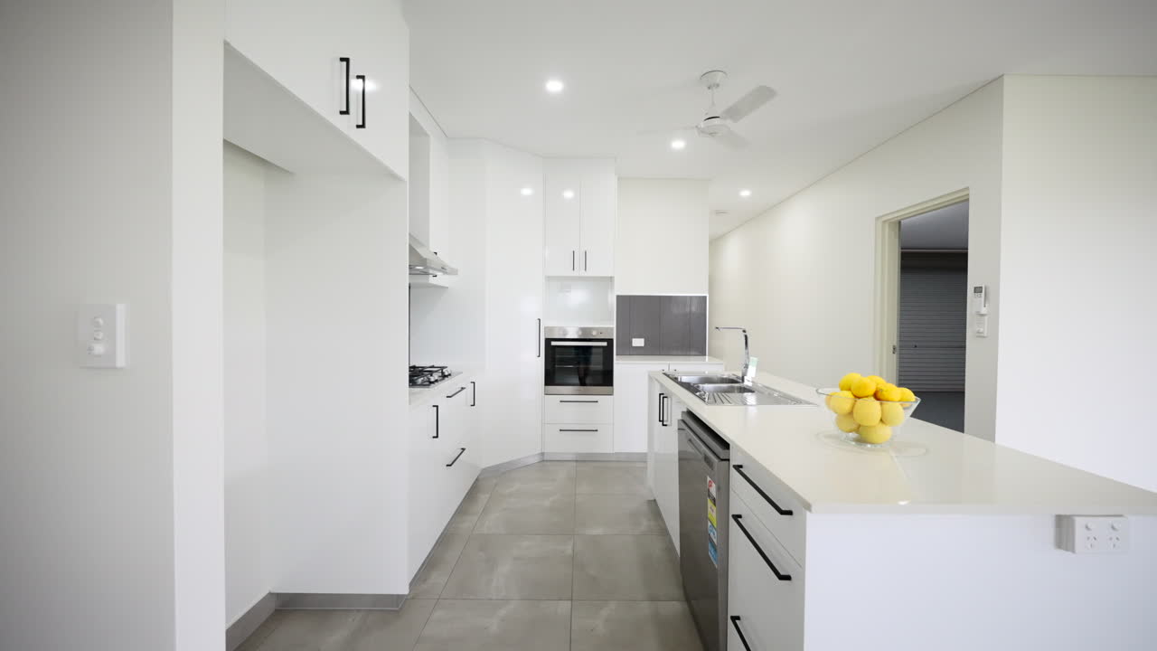 Moderna y elegante cocina diáfana totalmente blanca, con encimeras de gas y electrodomésticos de acero inoxidable.