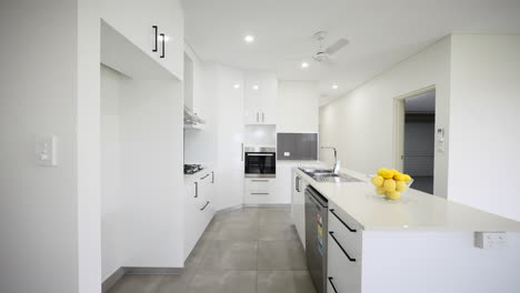 modern sleek open plan all white kitchen with, gas cooktops, and stainless steel appliances