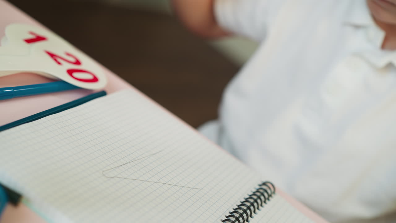 Little boy draws triangle with ruler and by hand in copybook