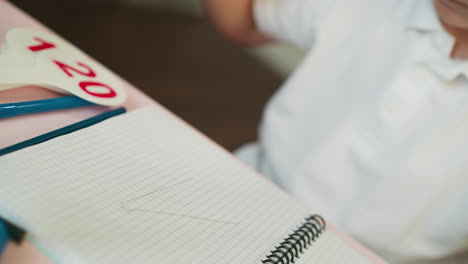 Little boy draws triangle with ruler and by hand in copybook