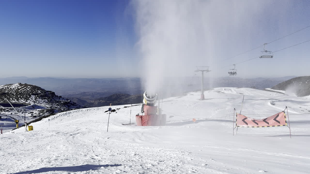 snow machine operating on ski slope with ski lift in background