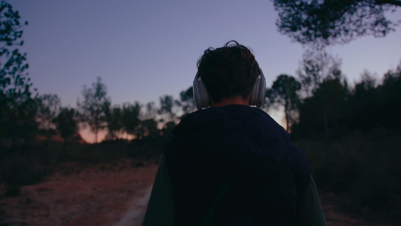 Person Walking in Nature at Dusk with Headphones