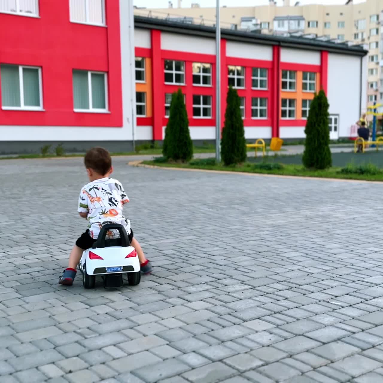 Simpatico bambino che gioca all'aperto con la sua macchinina bianca. Sorridente, si diverte durante l'estate