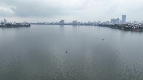 Wide-expanse-of-Tay-Ho-Lake,-twin-canoes-gently-cut-through-water-surface