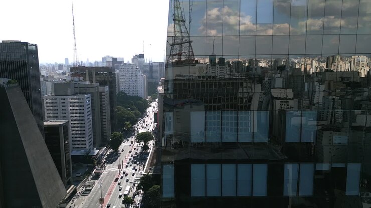 Imagens aéreas revelando a principal avenida em São Paulo por trás de um arranha-céu espelhado