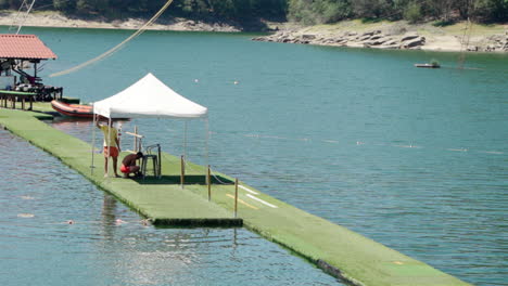 men fixing something on the jetty under the white tent in an aqua park in portugal - wide shot
