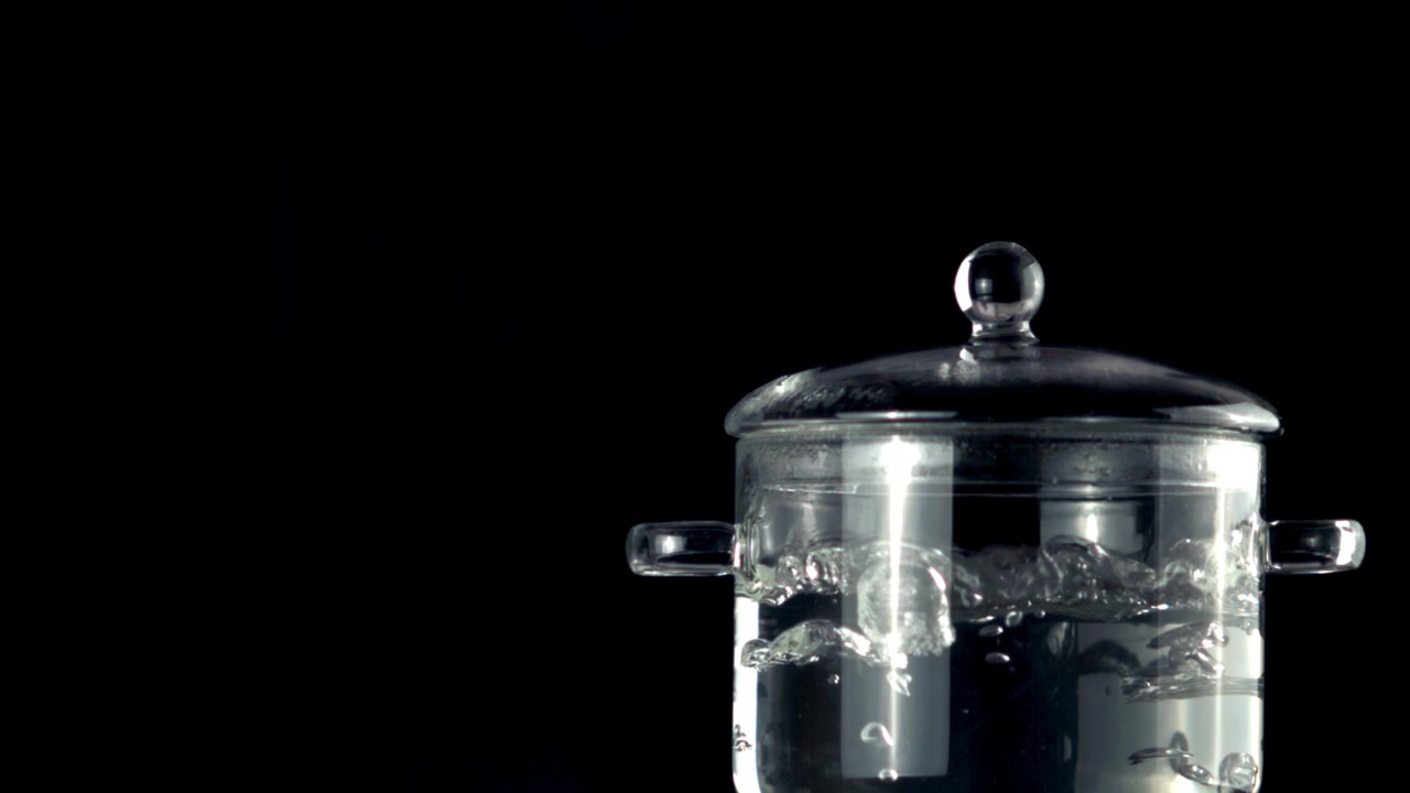 Water Boiling in a Transparent Glass Pot on Black Background