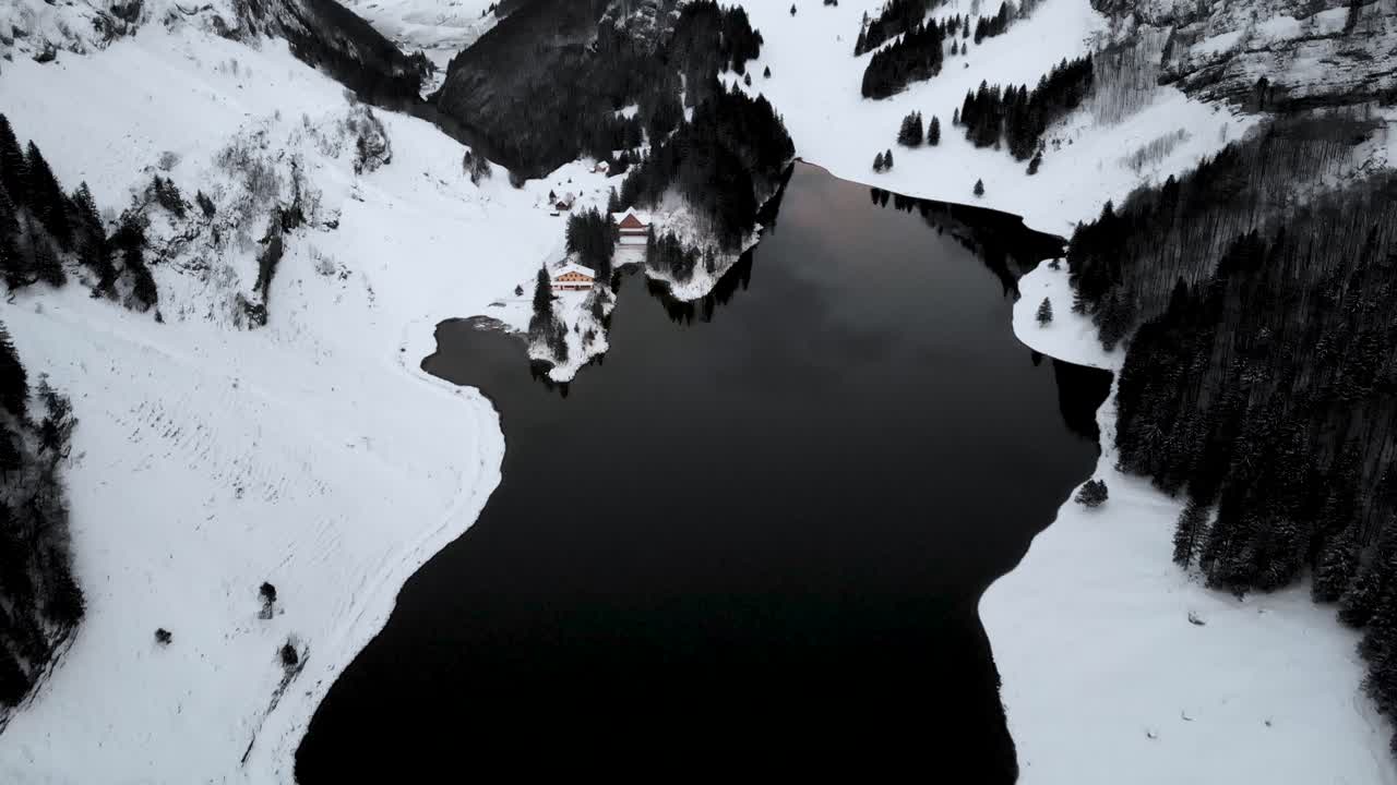 İsviçre'nin Appenzell kentindeki Seealpsee Gölü üzerinde havadan uçuş, yukarı kaydırma hareketiyle kar ve kayalıklarla dolu kış manzarasını ortaya çıkarıyor.