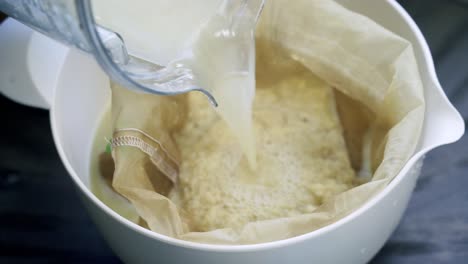 verter agua en una bolsa de nueces llena de pulpa de jengibre fresco haciendo una deliciosa bebida saludable