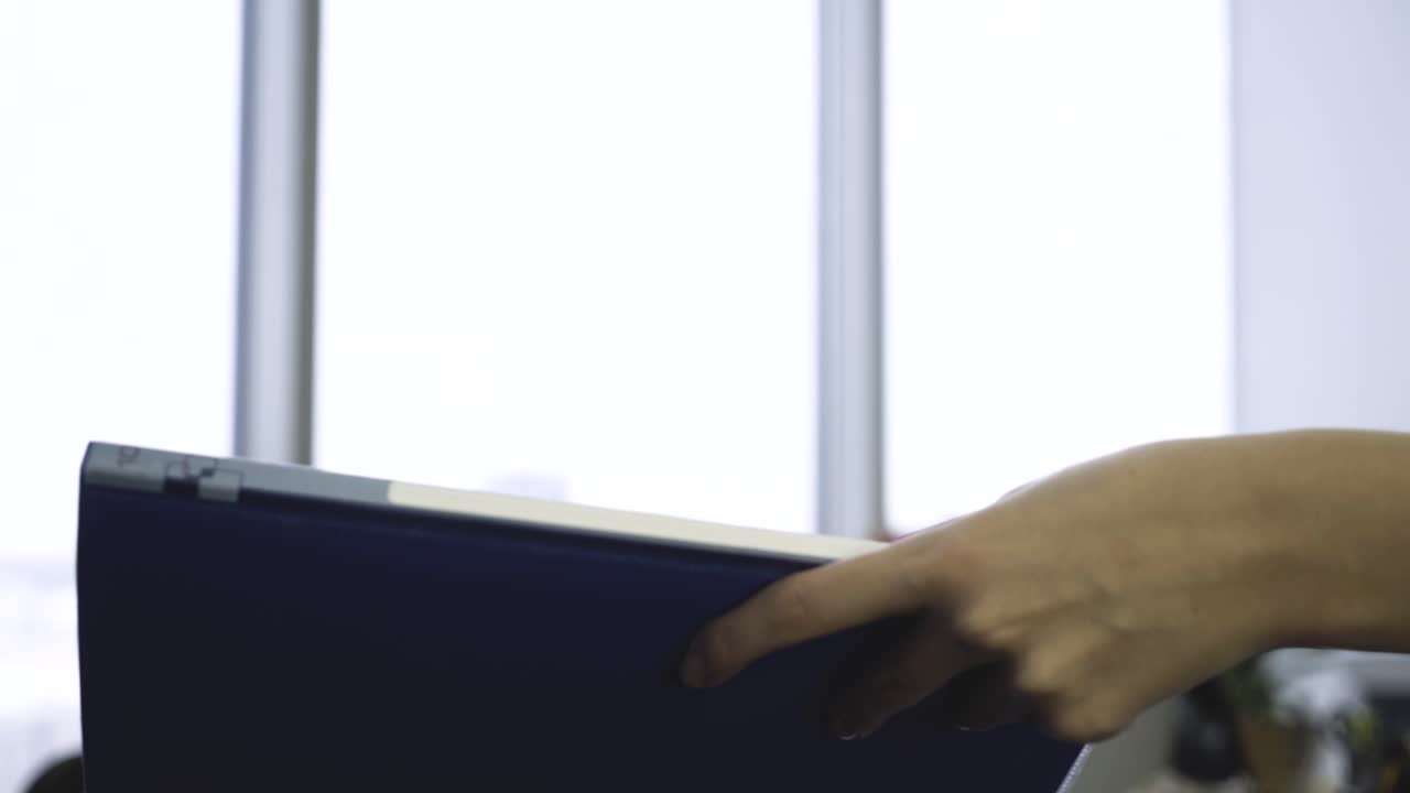 persona sosteniendo una carpeta cerca de una ventana