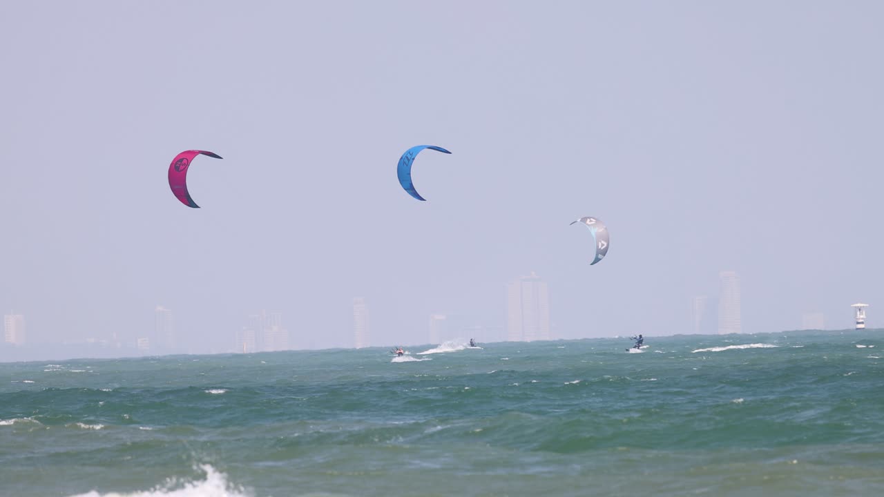 카이트 서퍼 들 은 바다 의 흔들리는 파도 를 가로질러 미끄러진다