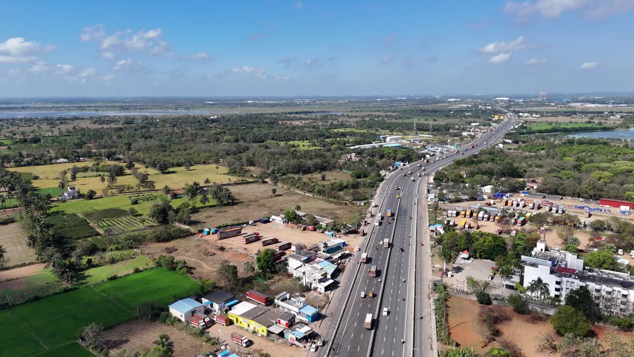 Aerial view of a busy Indian highway. It cuts through farmlands and developing areas, with a large lake in the distance. Ideal for infrastructure, urban expansion, and travel themes. Chennai-Bangalore