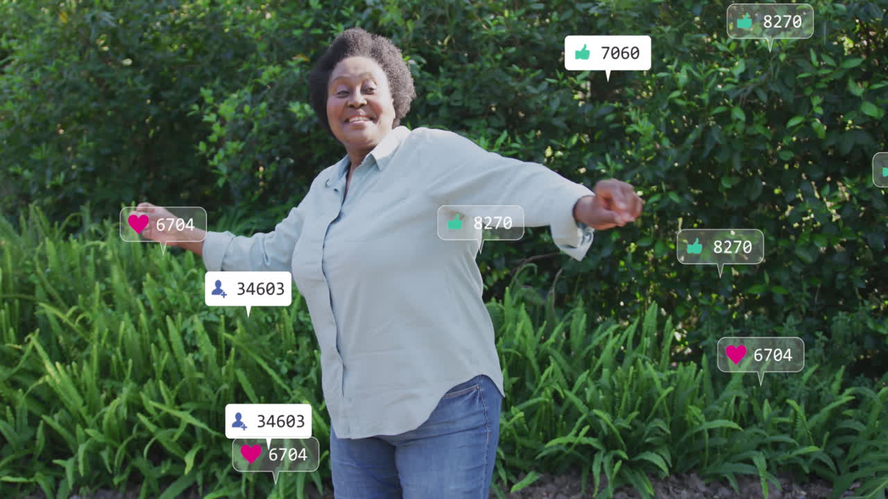 animación de iconos de las redes sociales sobre una feliz mujer mayor afroamericana bailando en el jardín