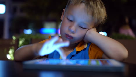 bored little boy using pad in cafe