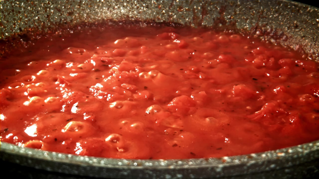 Salsa di pomodoro rosso vivace che sobbolle e ribolle in padella