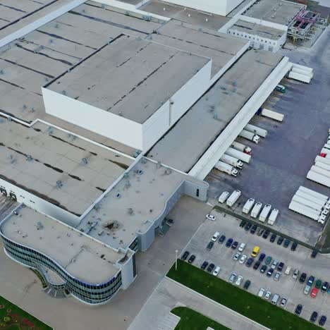 huge complex and parking places. roofs of industrial buildings with trucks and car parking in summer. top aerial view.