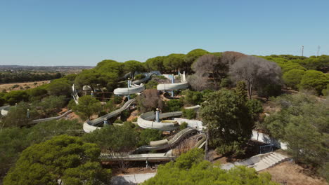 Aerial-flight-over-abandoned-water-park-rotten-between-green-blooming-trees-in-Portugal