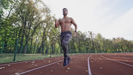 handsome man training on the field stadium. young muscular athlete runs on the sports track outdoors. healthy lifestyle.