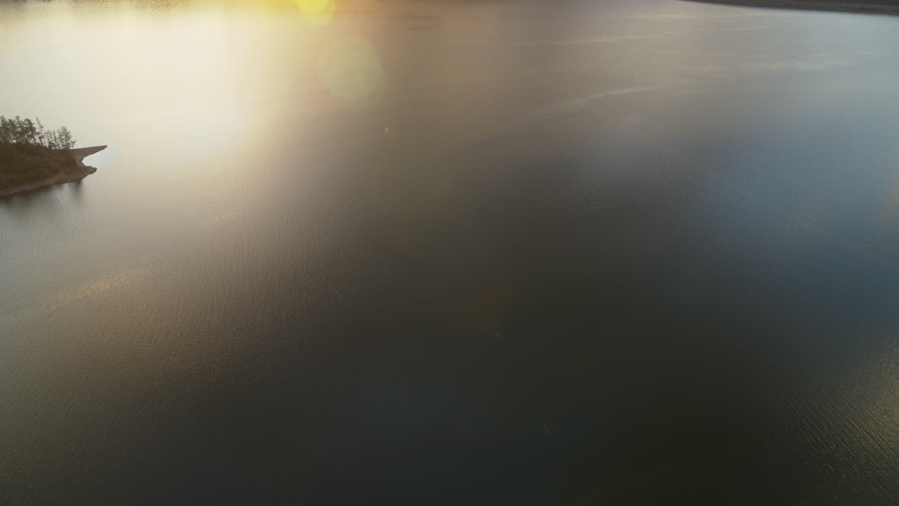 Pan up over Whiskeytown Lake revealing a mountain with the sunrise coming up over it