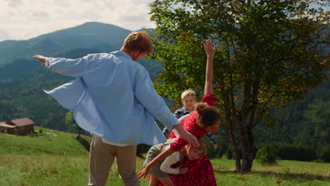 familia corriendo con los brazos extendidos en green hill. padres jugando con sus hijos.