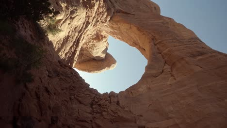 pan vertical derecho de mano tiro de paisaje ancho de grandes formaciones de arco de piedra arenisca naranja natural impresionante con el sol brillando a través de ellos en una caminata en el sur de utah en una soleada mañana de primavera cálida