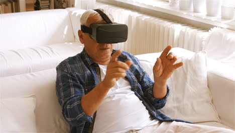 hombre mayor usando auriculares de realidad virtual en la sala de estar