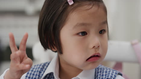 귀여운 아시아 소녀가 아침 식사를 하고 부 ⁇ 에서 시리얼을 즐기고 학교 유니폼을 입고 준비하고 있습니다.