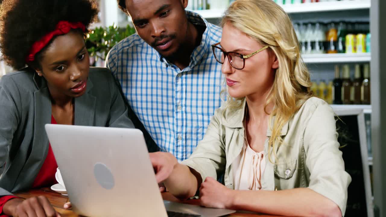Friends interacting with each other while working on laptop