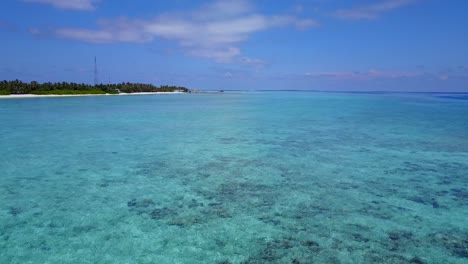 vista desde las aguas azules cristalinas de una isla tropical cubierta de palmeras y rodeada de playas blancas y polvorientas