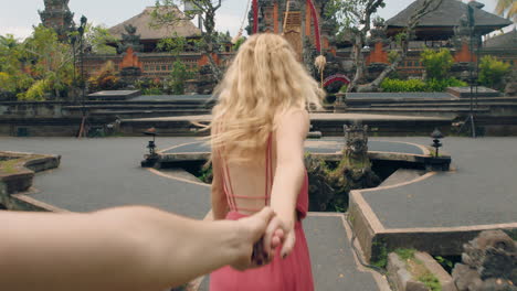 travel couple holding hands excited woman leading boyfriend exploring saraswati temple having fun sightseeing culture of bali indonesia