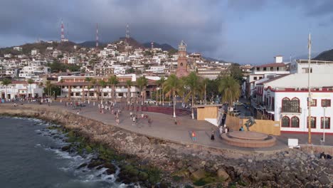 tourists stroll on puerto vallarta waterfront esplanade past los arcos