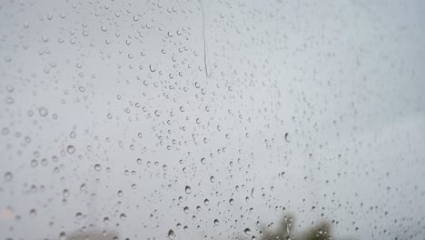 Se-Ve-Un-Primer-Plano-En-Cámara-Lenta-De-Fuertes-Gotas-De-Lluvia-A-Través-Del-Cristal-De-Una-Ventana.