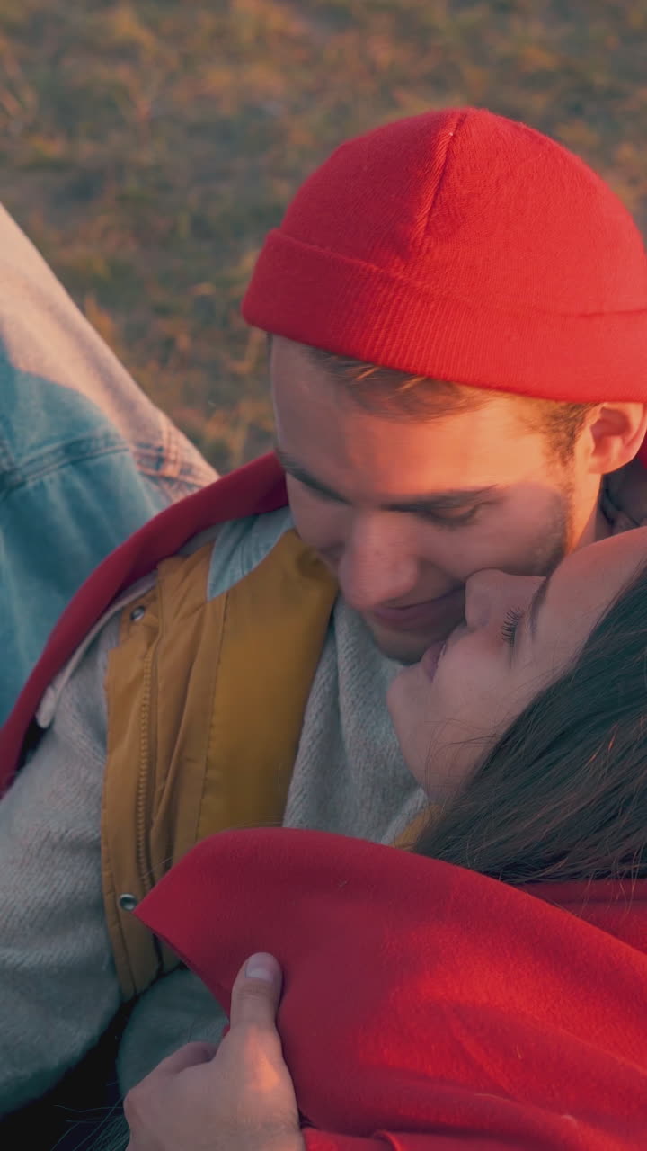 happy guy and girlfriend wrapped with plaid rest among friends in tourist camp in warm autumn evening closeup