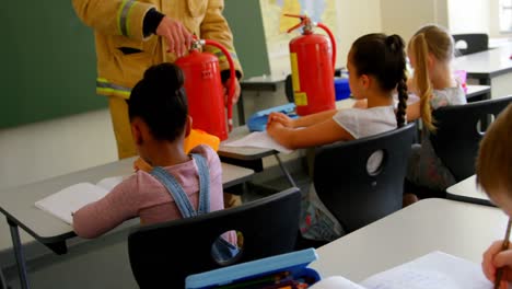 Männlicher-Kaukasischer-Feuerwehrmann-Unterrichtet-Schulkinder-Im-Klassenzimmer-über-Brandschutz-4k