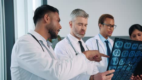 Close-Up-Of-Mixed-Races-Medical-Team-Specialists-Standing-In-Hospital-Talking-Discussing-Coronavirus-Disease-Treatment-Looking-At-X-Ray-Scan,-Colleagues-Discuss-Patient-Analysis,-Healthcare-Concept