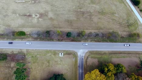 Este-Vídeo-Muestra-Un-Dron-Volando-Sobre-Nosotros-Siguiendo-A-Unos-Coches-Circulando-Por-Una-Carretera-Rural.