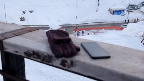 teléfono móvil y guantes dejados sentados en un riel de madera durante las nevadas invernales en la estación de esquí de gudauri en georgia