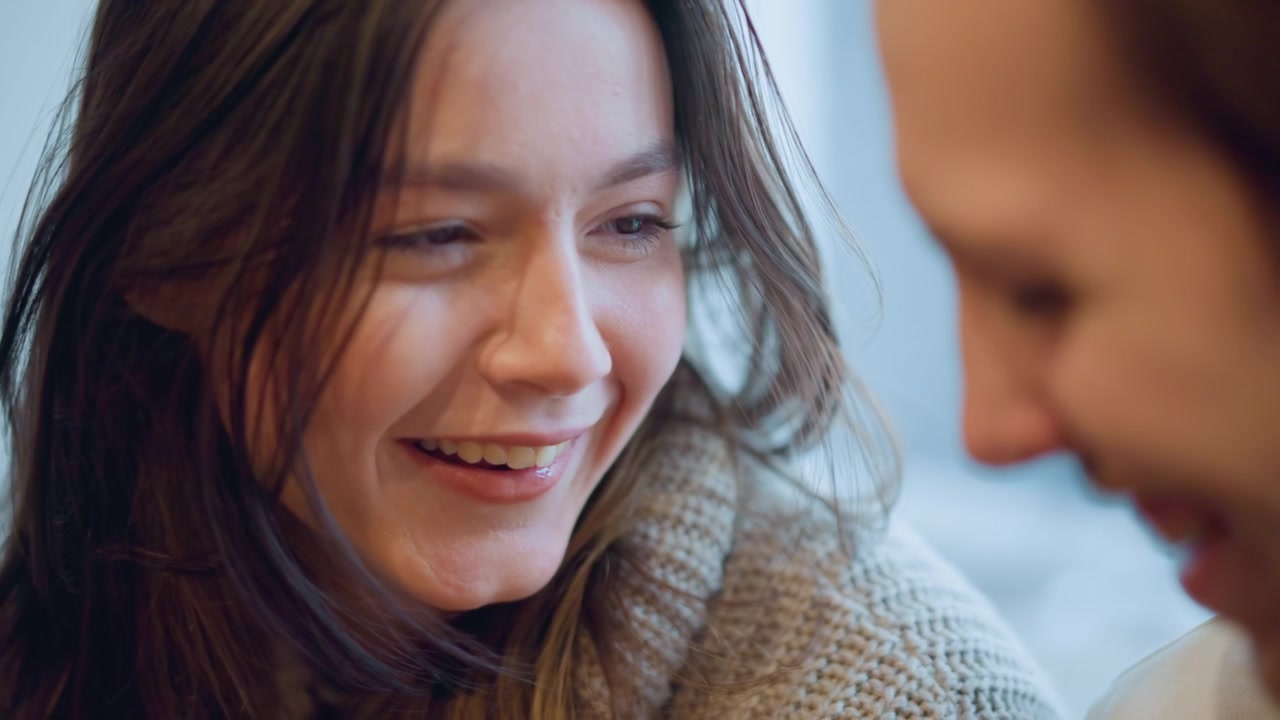 Close up of woman with long brown hair wearing knitted sweater showing various facial expressions including smiling and sticking out her tongue. background is softly blurred suggesting