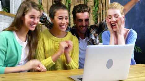 grupo de amigos usando una computadora portátil mientras toman café