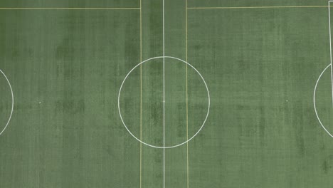 the drone records an upward shot of the football stadium, commencing with the center circle and concluding with the entire pitch occupying the frame