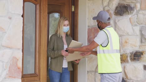 delivery man delivering package to woman wearing face mask at home