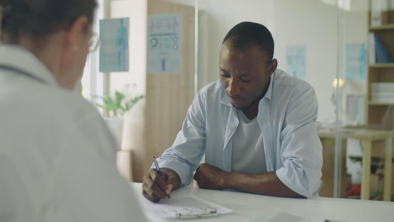 Male Patient Signing Medical Agreement with Doctor